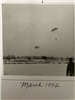 Black and white photo of people parachuting over the water