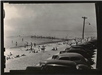 Black and white photo of cars lined up and people at the beach