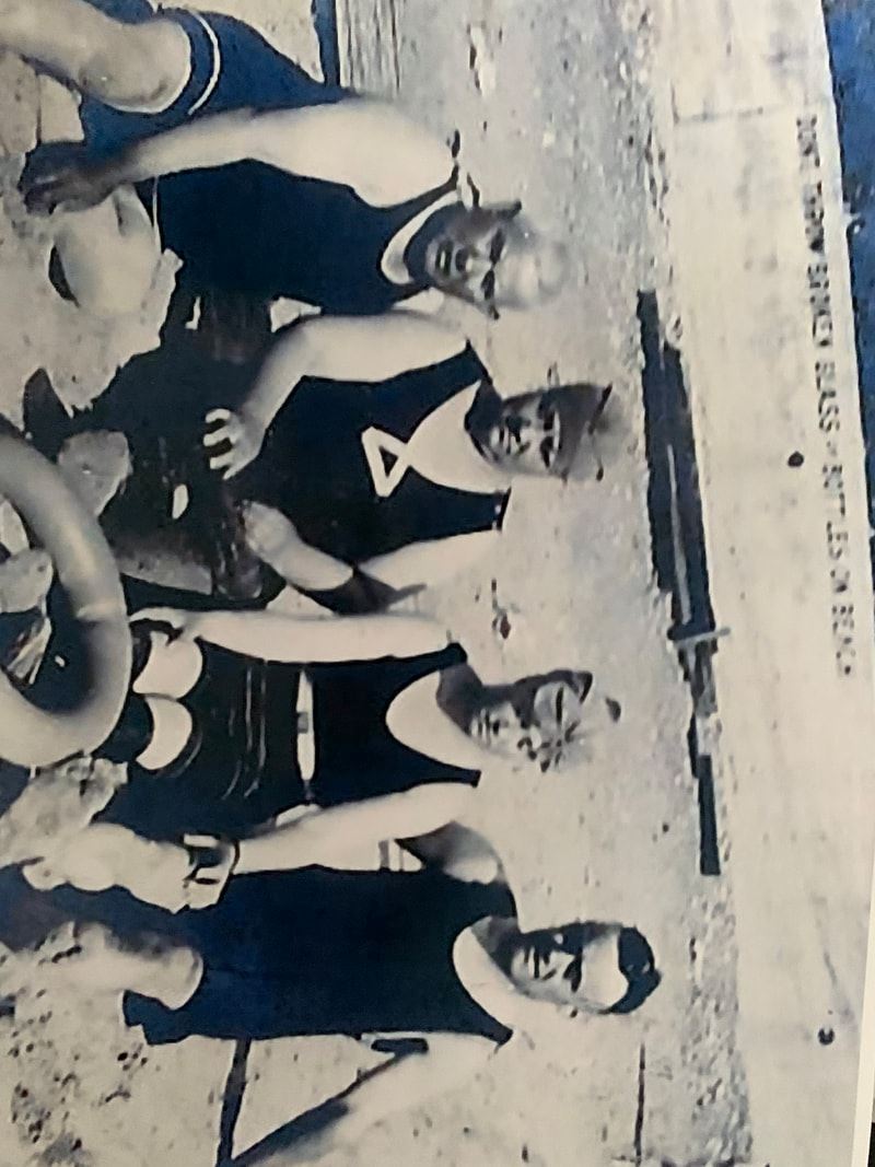 Black and white photo of people in bathing suits sitting on the beach