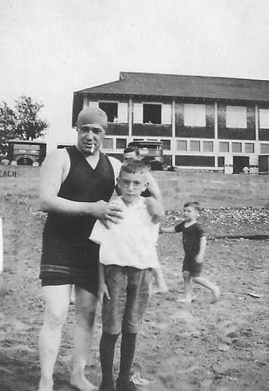 Black and white photo of adult and children at the beach