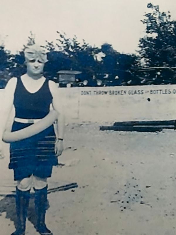 Black and white photo of person wearing bathing suit and flotation device at the beach